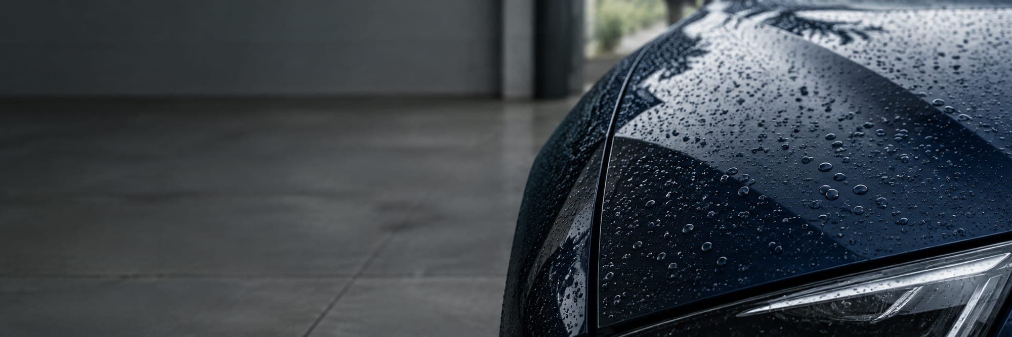 Water beading on the sealed paintwork of a dark blue car