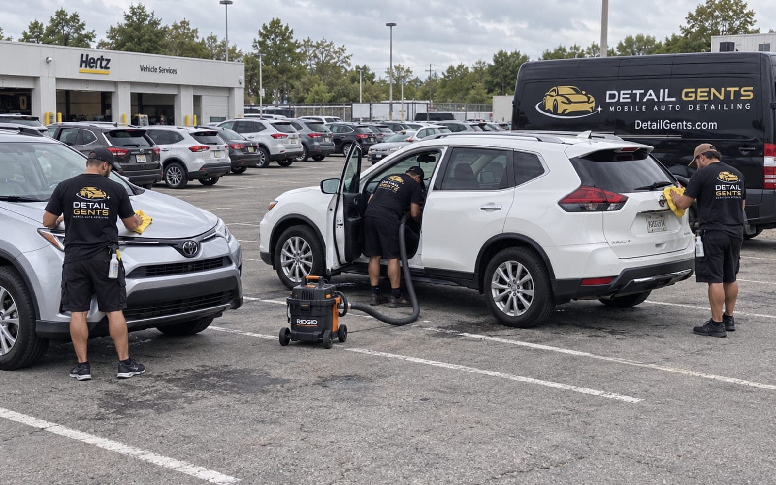Three Detail Gents detailers wiping down rental SUVs in a line at a rental branch lot, with a branded van parked alongside