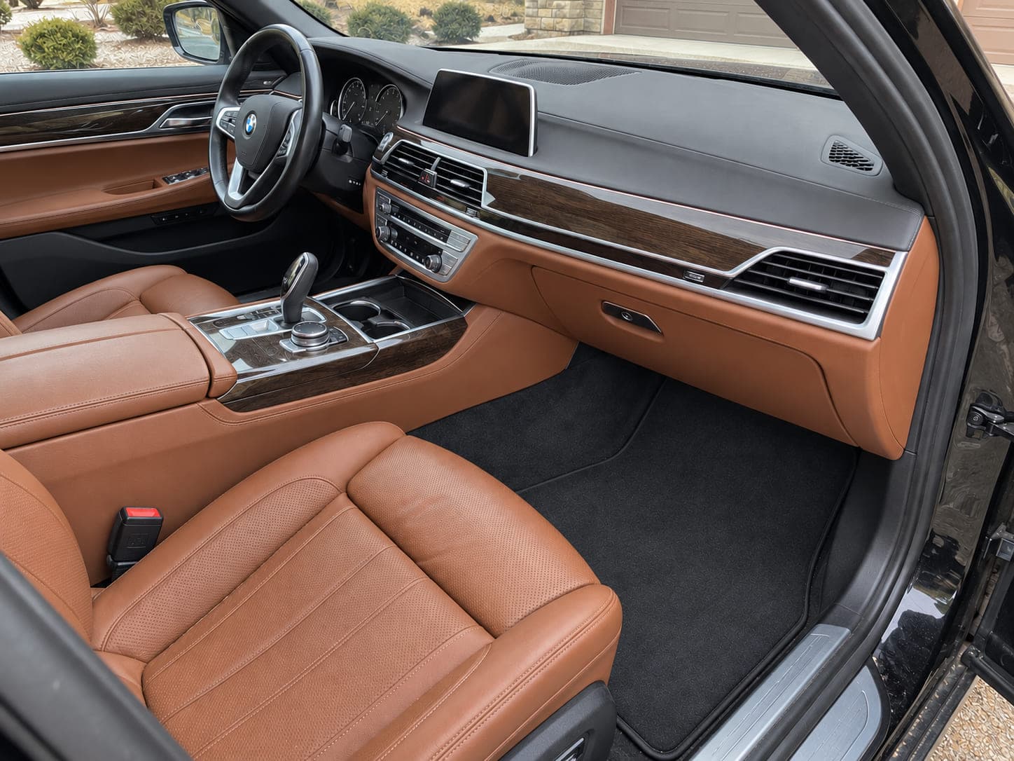 The cognac leather front cabin and wood trim of a BMW 7 Series after an interior detail