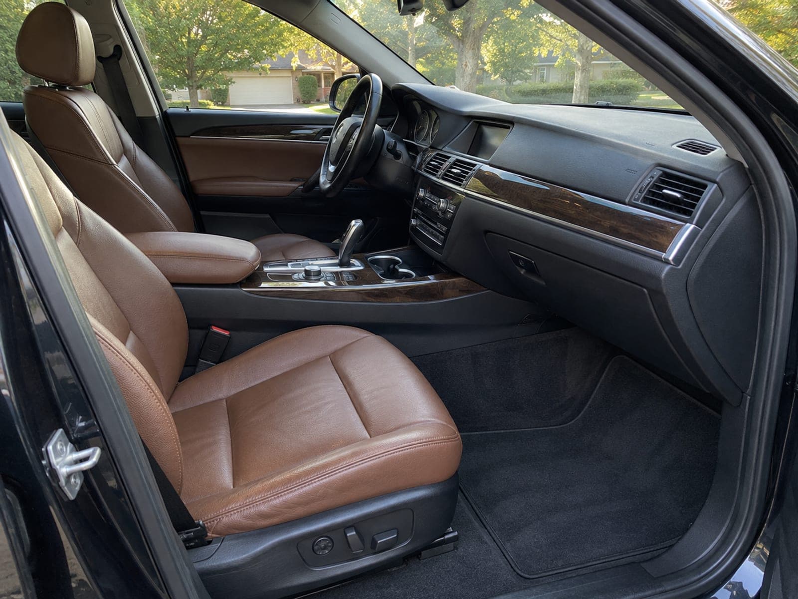 The front cabin of a BMW SUV with cognac leather seats, a dressed dashboard and freshly vacuumed carpet after an interior detail