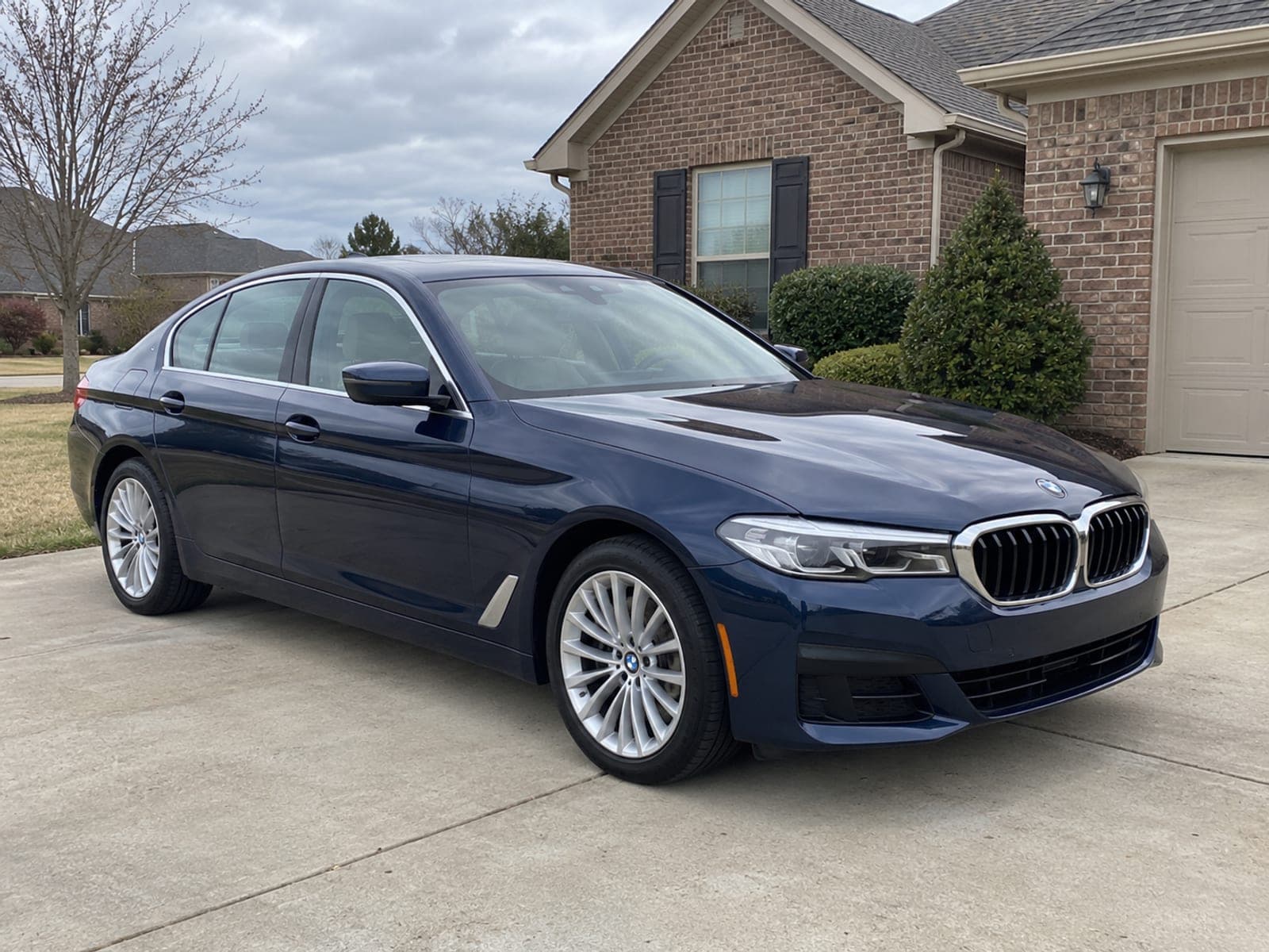 A dark blue BMW 5 Series on a residential driveway with the paintwork clean and even